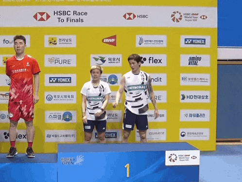 three athletes stand on a podium sponsored by hsbc and yonex