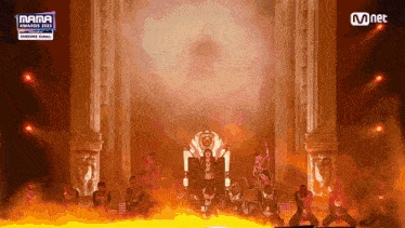 a woman in a throne is surrounded by a group of dancers on a stage that says mama awards 2021