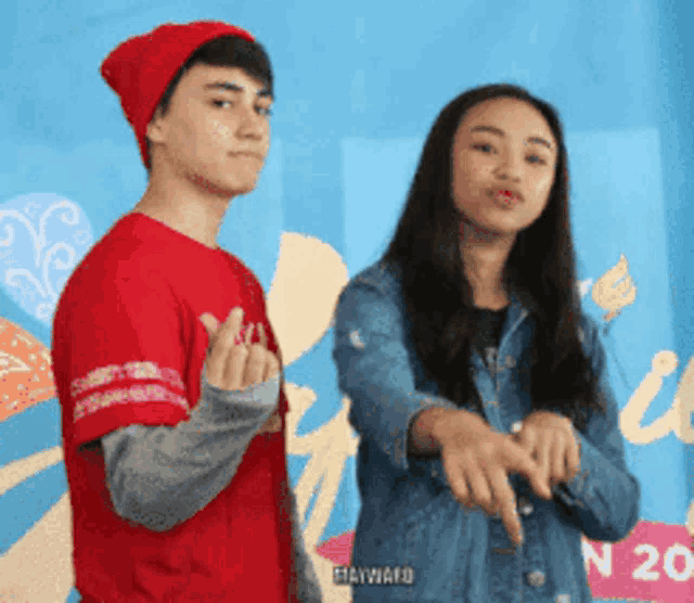 a boy in a red shirt and a girl in a denim jacket are posing for a photo