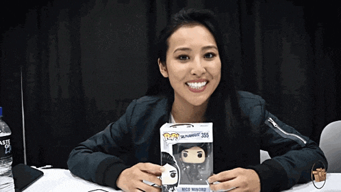 a woman is holding a funko pop of nico minono