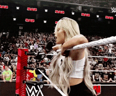 a woman is in a wrestling ring with the word raw on the walls behind her