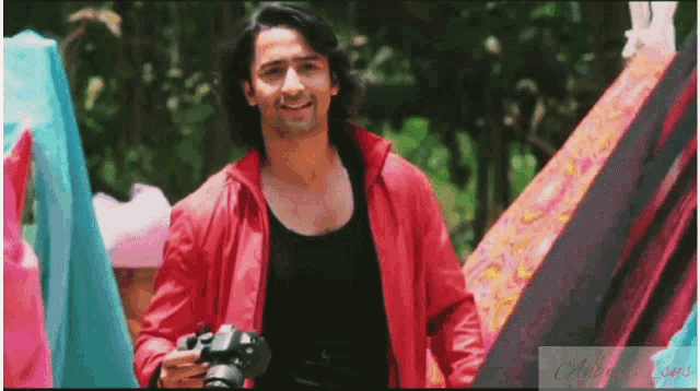 a man in a red jacket holds a camera in his hand