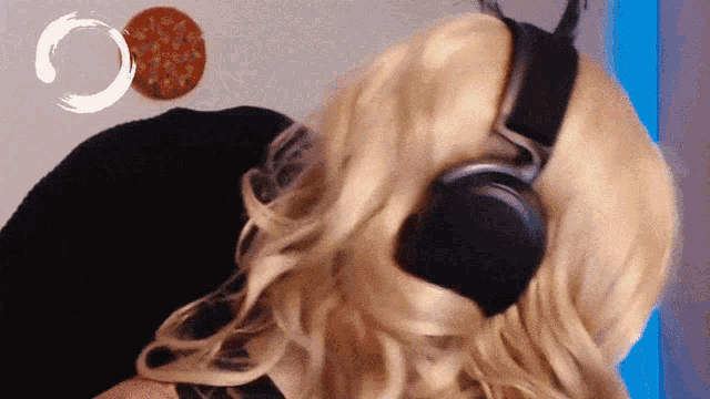 a woman wearing headphones looks at a pizza on the wall