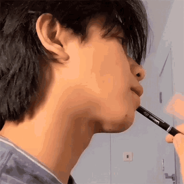 a close up of a person 's face with a pen in his mouth .
