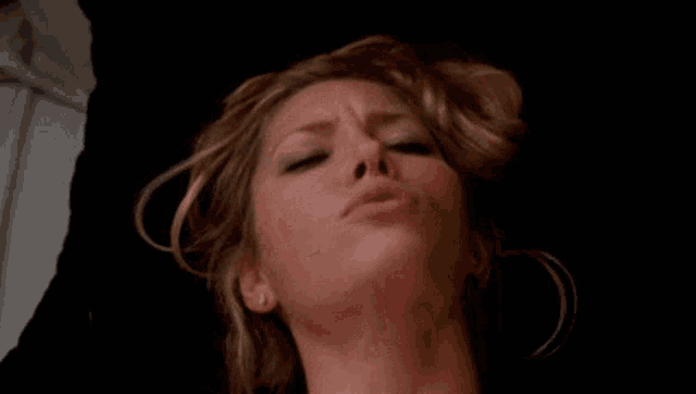 a close up of a woman 's face while laying on a bed with her eyes closed .