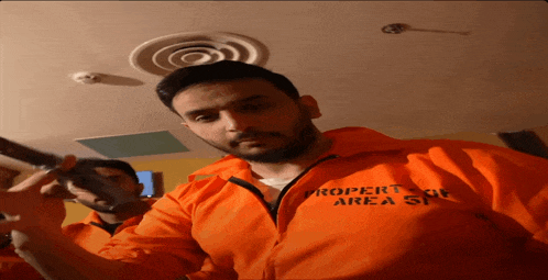 a man wearing an orange jacket that says " property of area 51 "