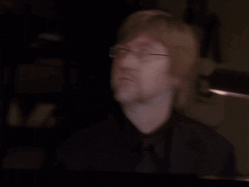 a man with glasses and a beard is looking up