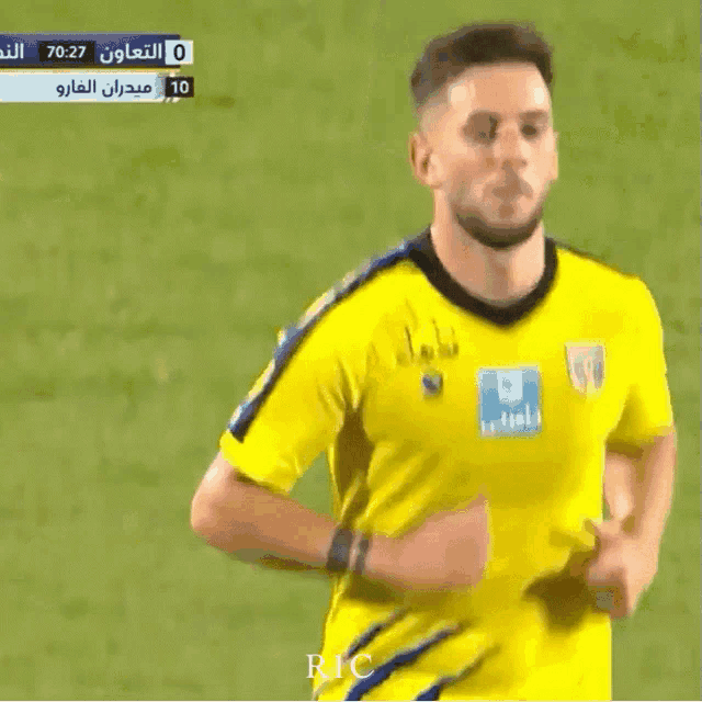 a soccer player wearing a yellow jersey with blue stripes is running on a field