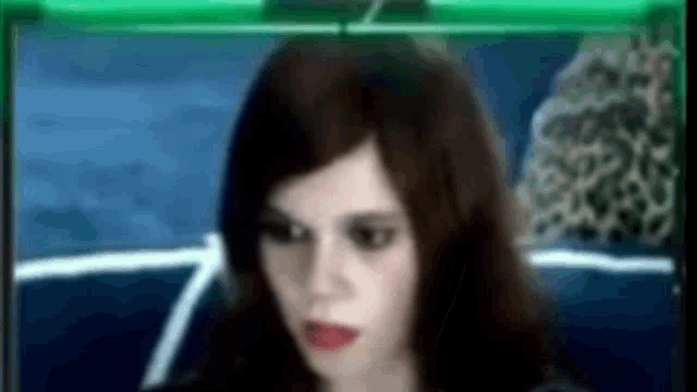 a woman with dark hair and red lips is looking at the camera .