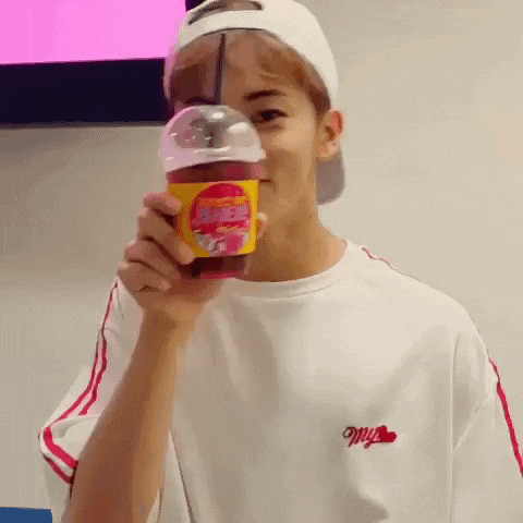 a young man wearing a white hat and a white shirt is holding a cup of coffee .