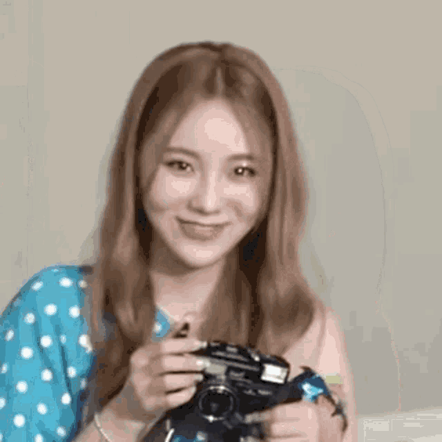 a woman is holding a camera and smiling .