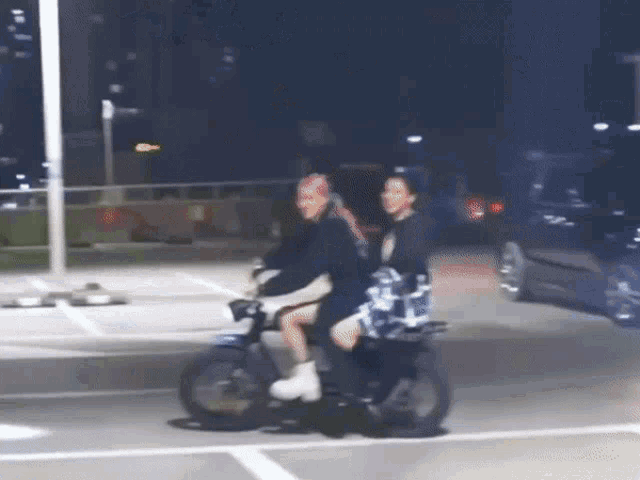 two people are riding a motorcycle down a street at night