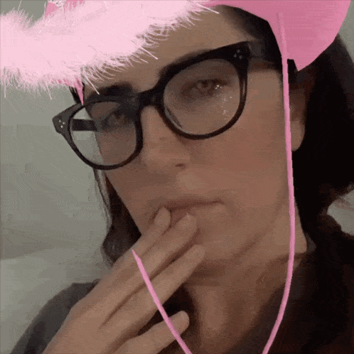 a woman wearing glasses and a pink hat with feathers