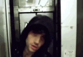 a man wearing a hooded jacket is standing in a doorway .