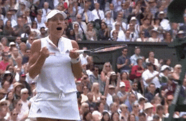 a woman in a white dress is holding a tennis racket in front of a crowd .
