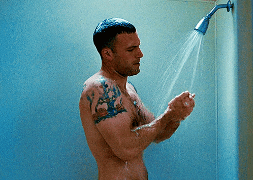 a shirtless man with tattoos takes a shower