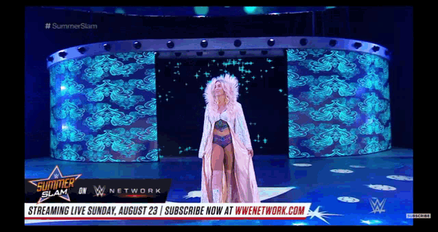 a woman in a white dress stands on a stage in front of a large screen that says summerslam on it