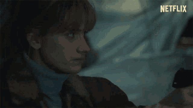a woman is sitting in a car looking out the window .
