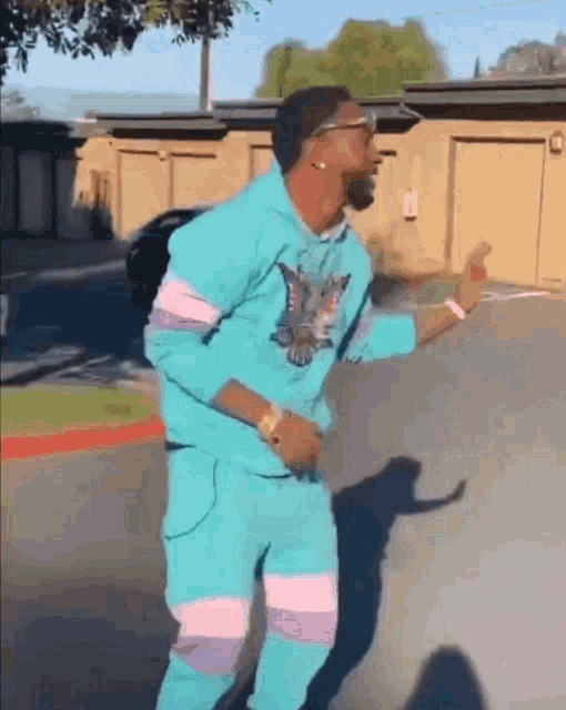 a man in a blue suit is dancing in a parking lot .