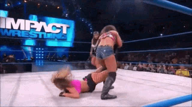 two women wrestling in a ring with a sign that says impact wrestling