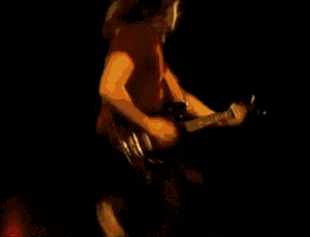 a man in a red shirt is playing a guitar on a stage