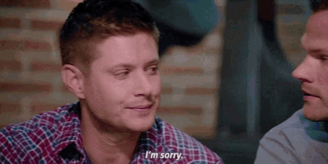 a man in a plaid shirt says i 'm sorry to another man