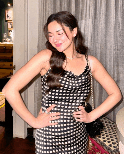 a woman in a black and white polka dot dress stands with her hands on her hips