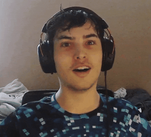 a young man wearing headphones looks at the camera