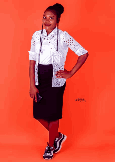 a woman wearing a white shirt and a black skirt poses for a photo