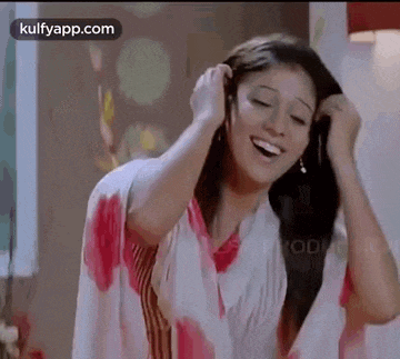 a woman in a pink and white dress is smiling while holding her hair .