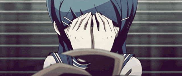a girl covering her face with her hands while looking at a book