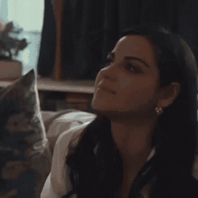 a woman is sitting on a couch with a cat in the background