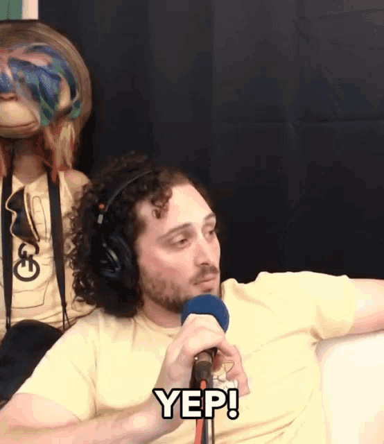 a man wearing headphones is talking into a microphone and says yep