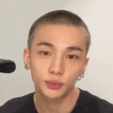 a close up of a man with a shaved head and earrings .
