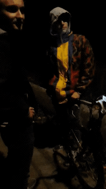 a man wearing a colorful jacket is standing next to a bicycle