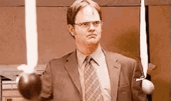 a man in a suit and tie is holding two lightsabers in his hands .
