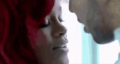 a man and a woman are kissing each other in front of a window .