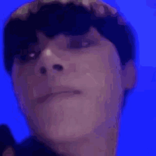 a close up of a person 's face with their mouth open and a blue background .