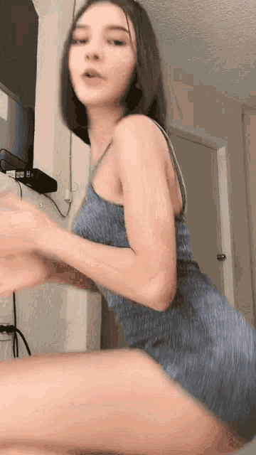 a woman in a blue dress is sitting in front of a tv