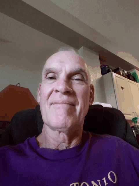 an older man wearing a purple shirt that says tonio