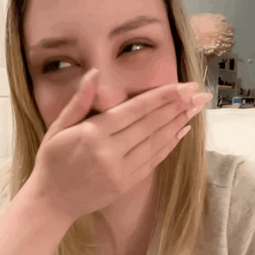 a woman covering her mouth with her hand while laughing
