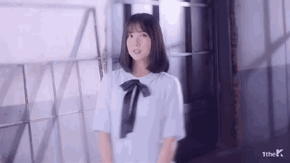 a young girl is standing in a hallway wearing a white shirt with a black bow .