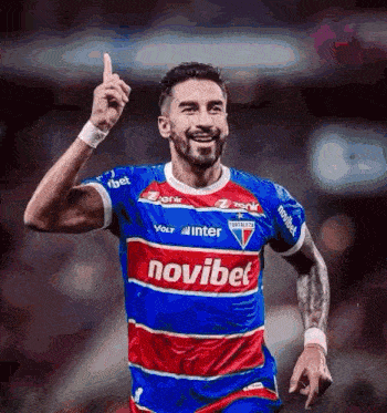 a soccer player wearing a blue , red , and white jersey with the word novibet on it .