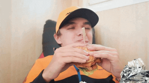 a man wearing a hat is eating a hamburger