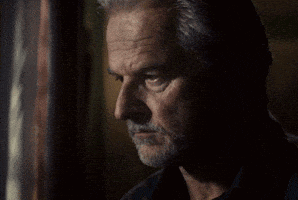 a close up of a man 's face with a beard in a dark room .