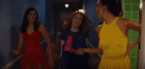 a group of girls are walking down a hallway .