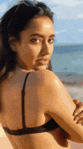 a woman in a bikini applying sunscreen to her arm