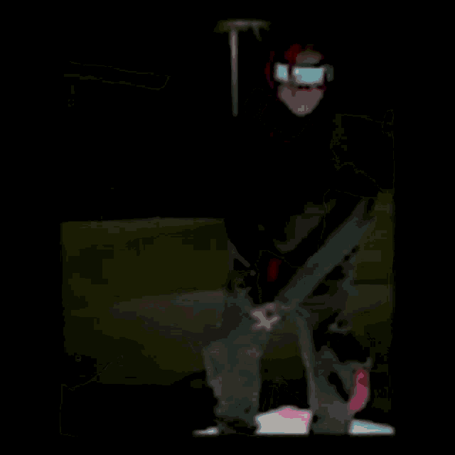 a person wearing a mask and a hoodie is standing in the dark