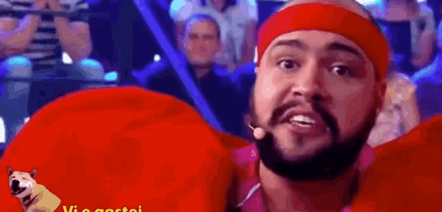 a man with a beard and a red headband is sitting in front of a crowd .