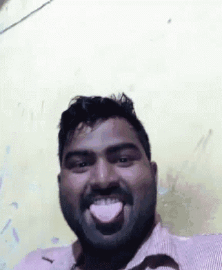 a man with a beard is sticking his tongue out while making a funny face .